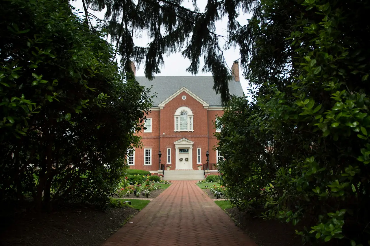 Brick building viewed from a tree-lined pathway.